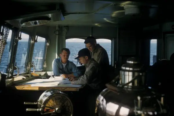 Tres personas leyendo documentos en un barco